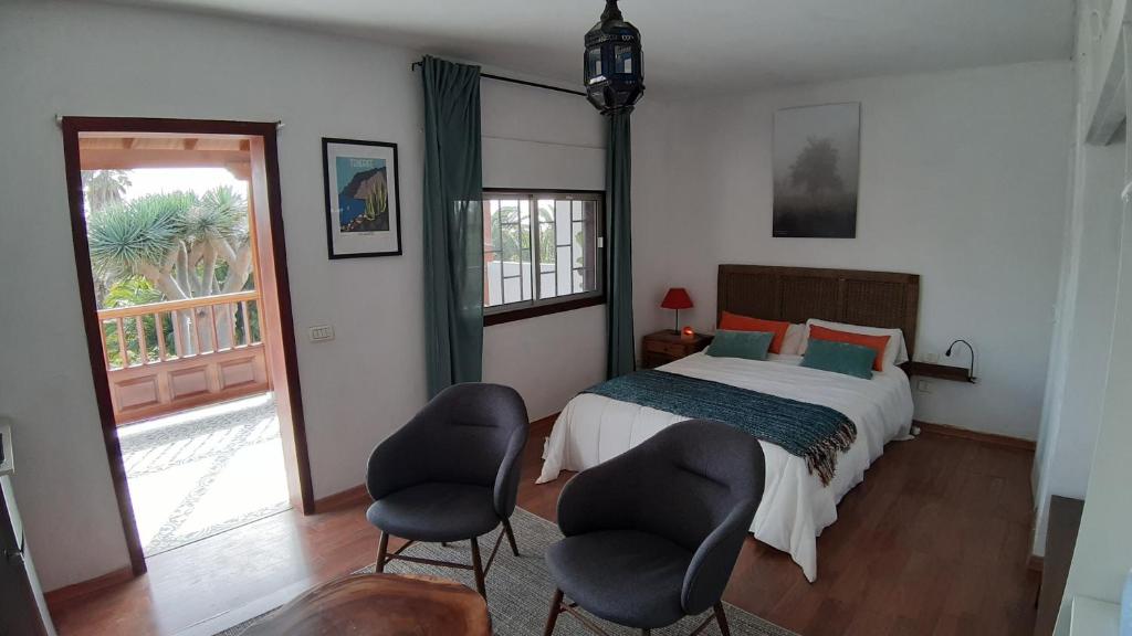 a bedroom with a bed and two chairs at Habitación con balcón y baños privados. in Tacoronte
