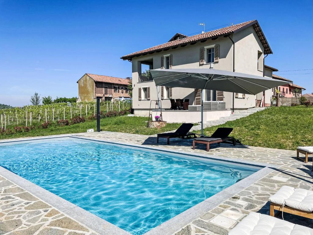 een zwembad met een parasol en een huis bij Apartment Cascina MonteRosa-1 by Interhome in Costigliole dʼAsti