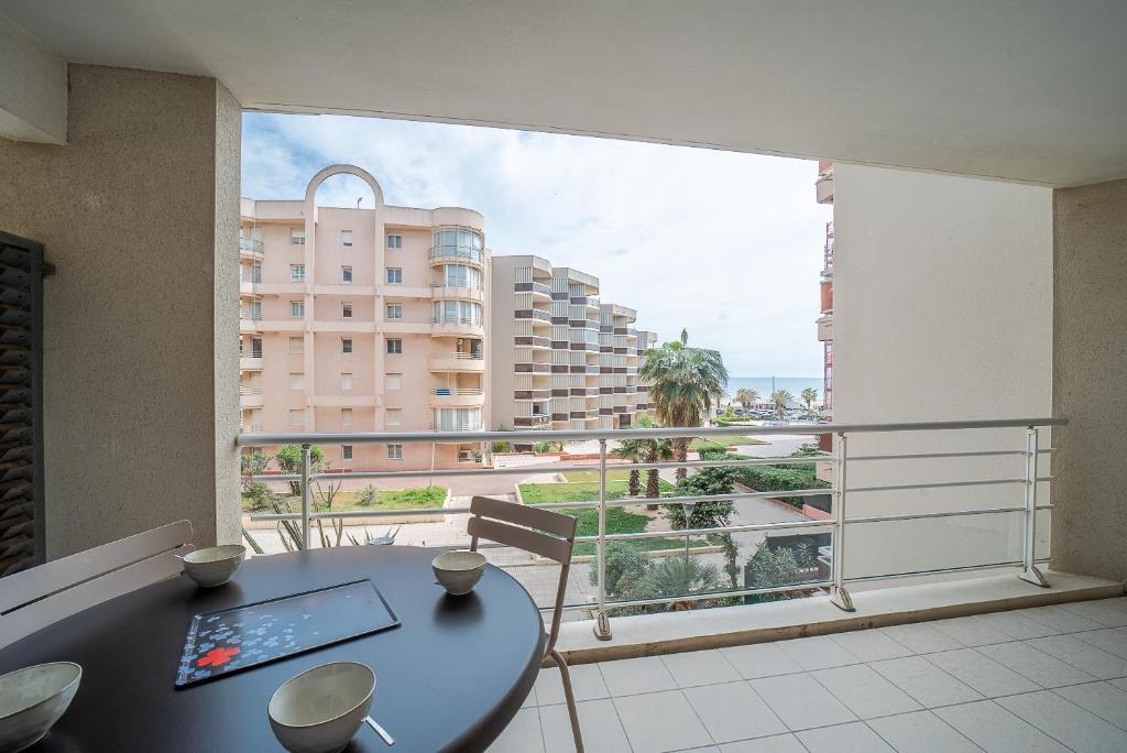 d'un balcon avec une table et une vue sur un bâtiment. dans l'établissement L'Oiseau Bleu - Vue mer montagne, 100m de la plage, à Canet