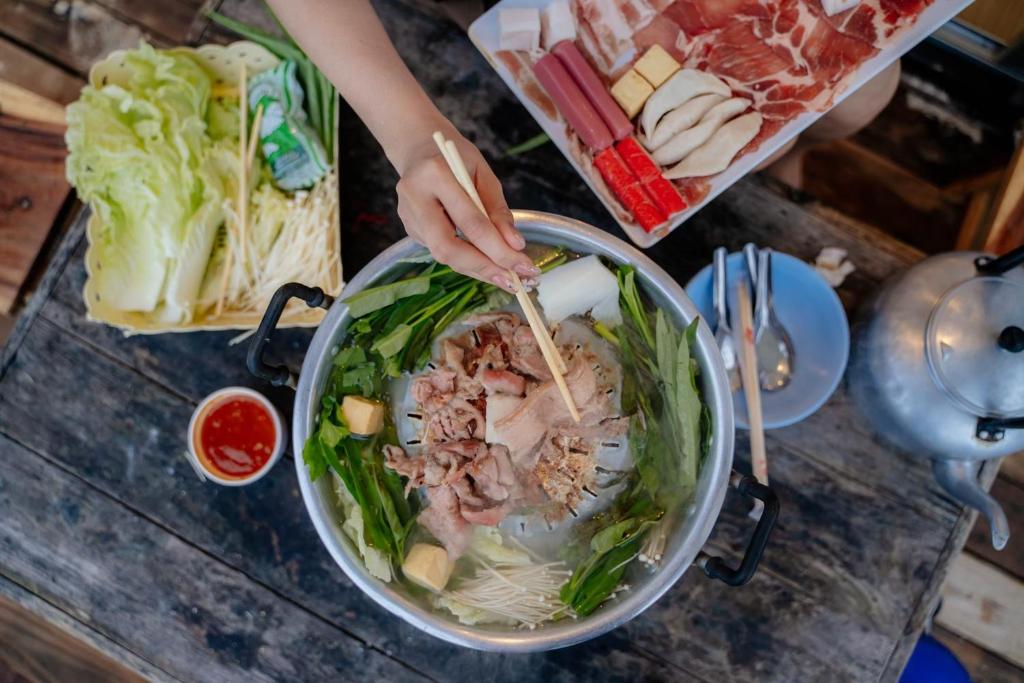 a person is stirring a bowl of food with chopsticks at ไร่ภูพญา ม่อนแจ่ม เชียงใหม่ in Mon Jam