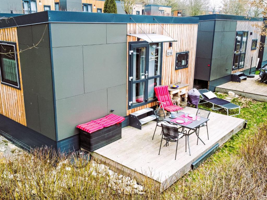 ein kleines Haus mit einer Terrasse, einem Tisch und Stühlen in der Unterkunft Holiday Home Auszeit Am See by Interhome in Wemding