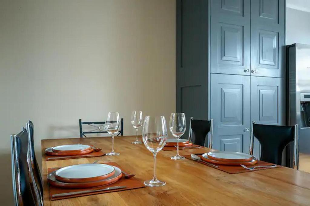 倫敦的住宿－Immaculate 4-Bed House in London，一张木桌,上面放有酒杯和盘子