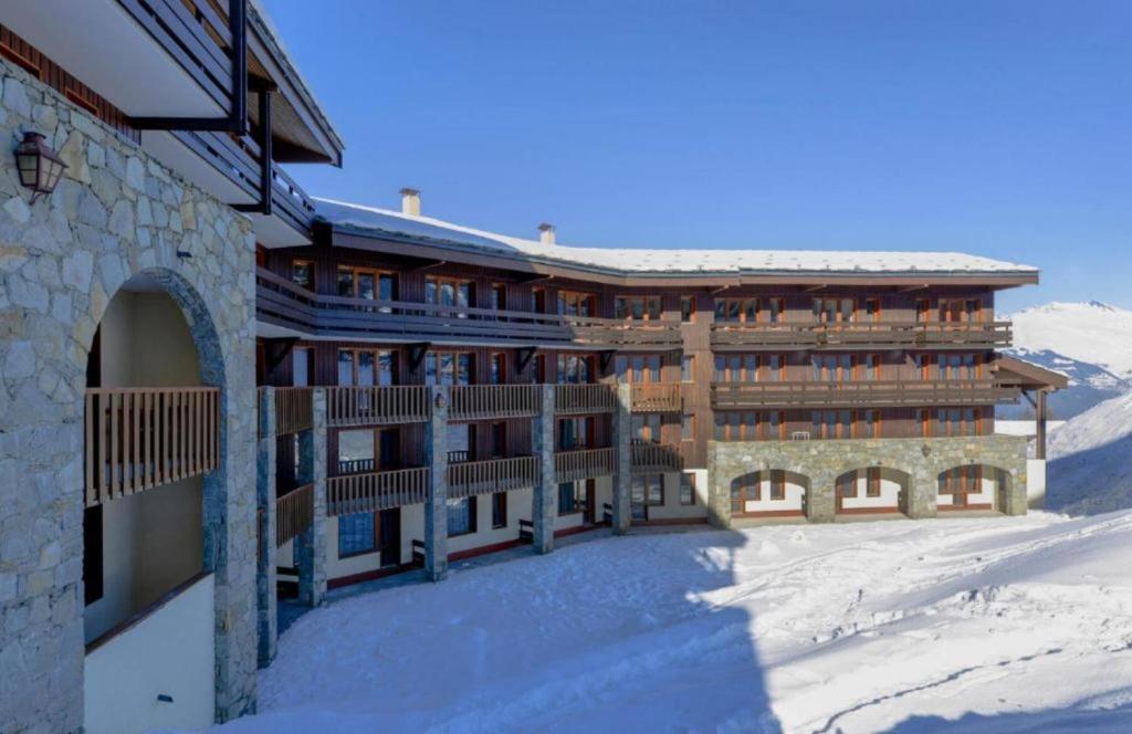 un grand bâtiment dans la neige avec une clôture dans l'établissement travelski home select - Résidence Backgammon, à La Plagne