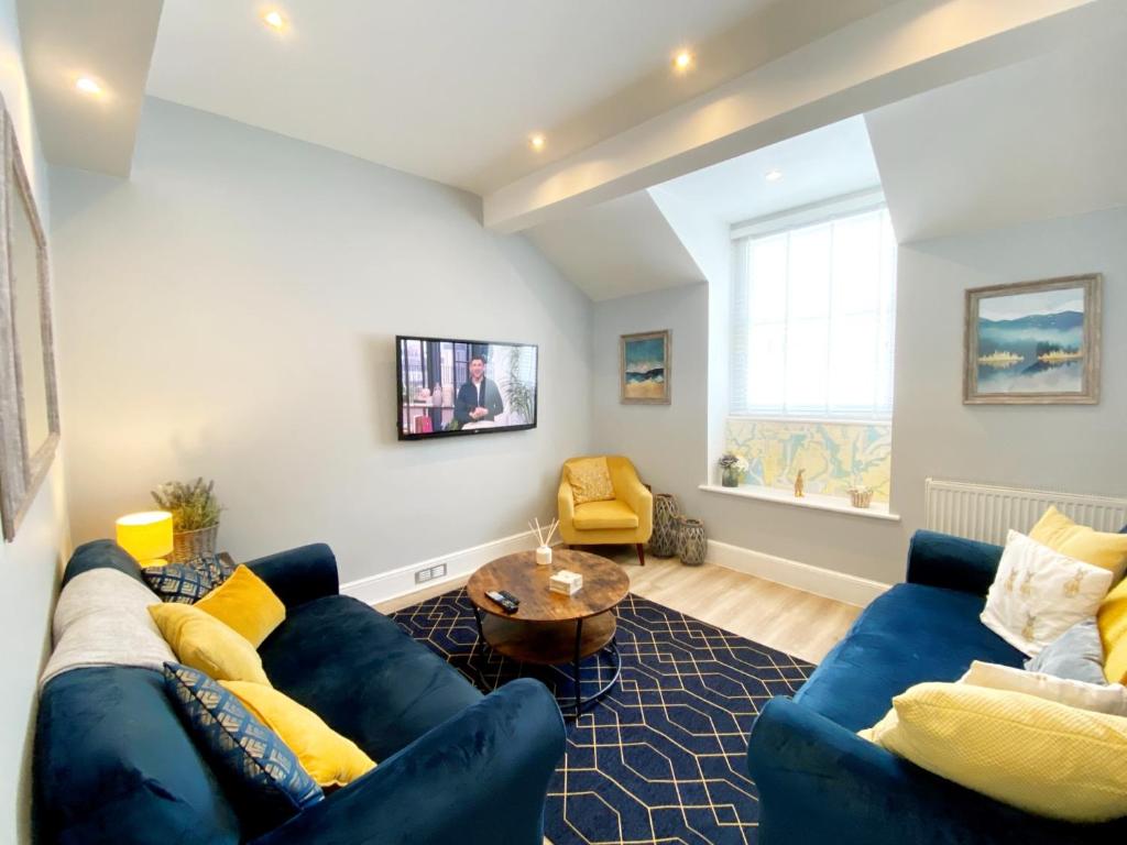 a living room with a blue couch and a table at Sovereign House Luxury Apartment in Torquay