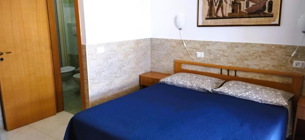a bedroom with a blue bed and a bathroom at Hotel Residence Villa Ascoli in Vieste