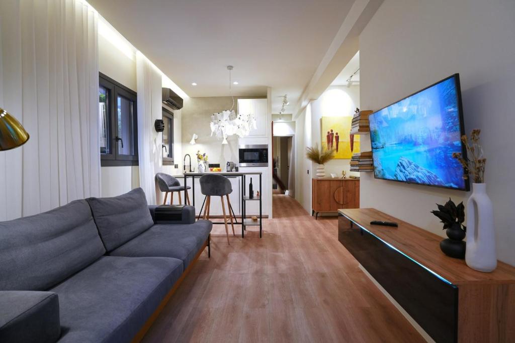 a living room with a couch and a tv on a wall at P Faliro Riviera Suite in Athens