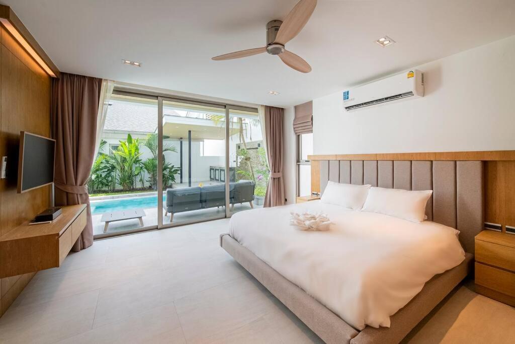 um quarto com uma cama, uma televisão e uma piscina em Modern Luxury 4BR pool villa Laguna Bangtao Beach em Ban Pak Lak
