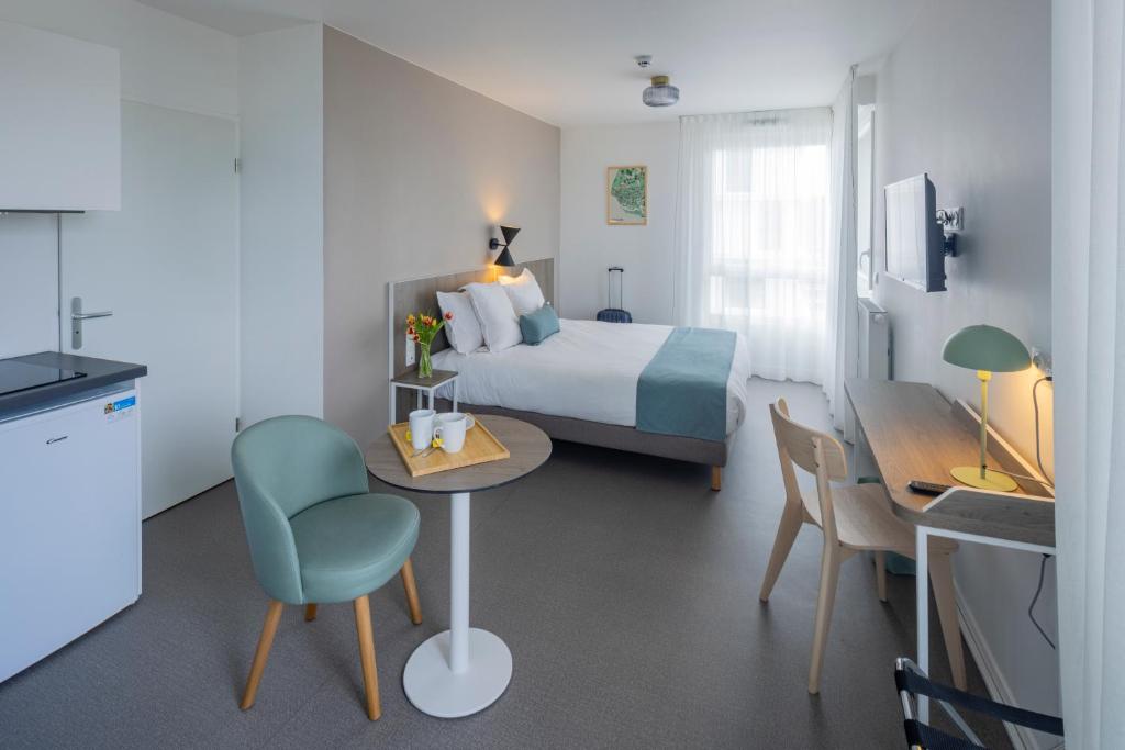 Habitación de hotel con cama, mesa y sillas en All Suites Appart Hotel Le Havre en Le Havre
