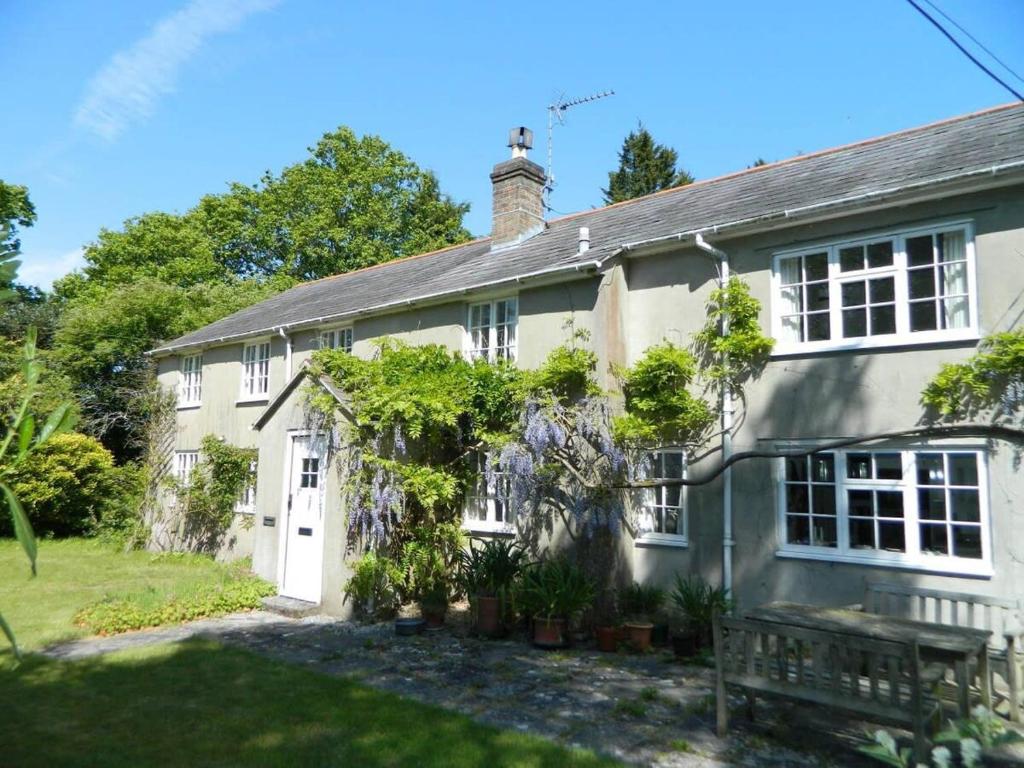 een oud huis met een bankje ervoor bij River Cottage a country retreat in wooded gardens in East Stoke