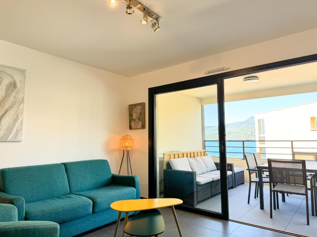 a living room with a blue couch and a table at Fronte di Mare 2 chambres vue mer - 1 in Propriano