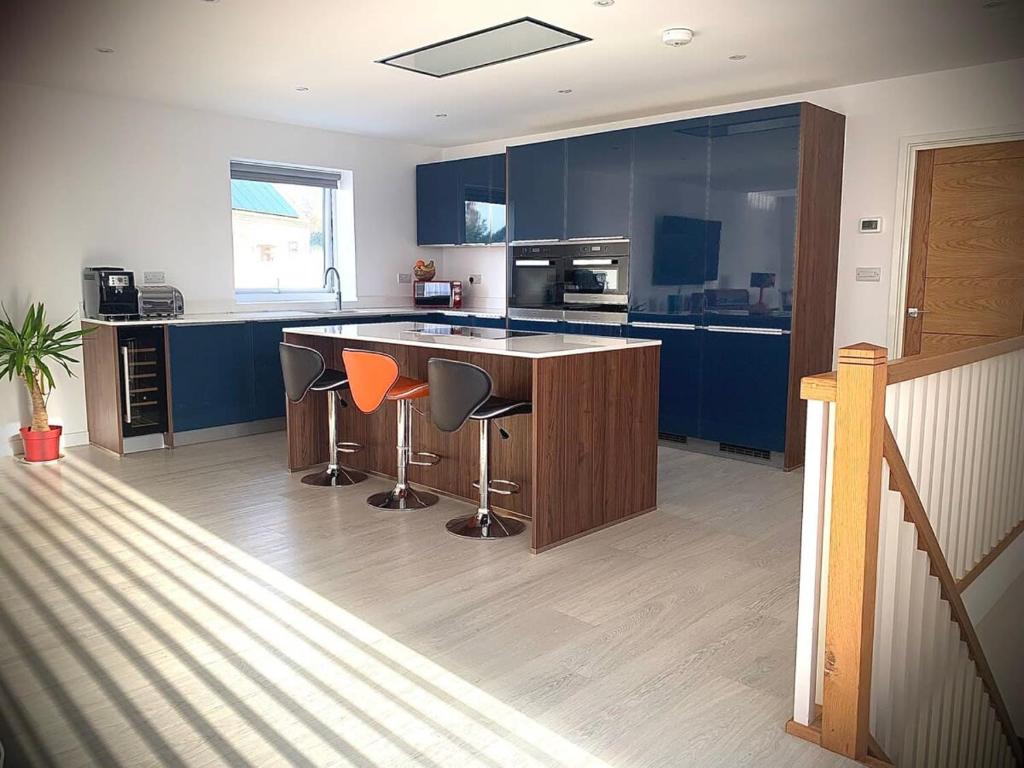 a kitchen with blue cabinets and orange bar stools at Relax in style at my stunning Holywell Beach home in Holywell Bay