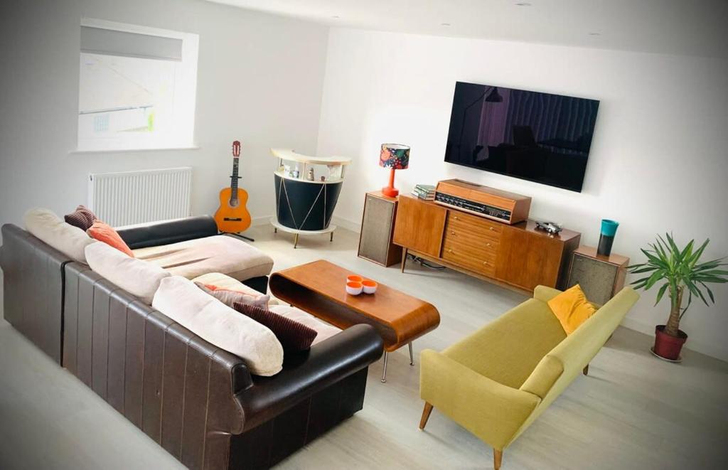 a living room with a couch and a tv at Relax in style at my stunning Holywell Beach home in Holywell Bay
