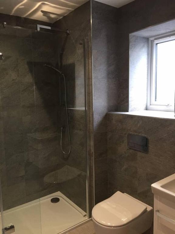 a bathroom with a shower with a toilet and a sink at Relax in style at my stunning Holywell Beach home in Holywell Bay