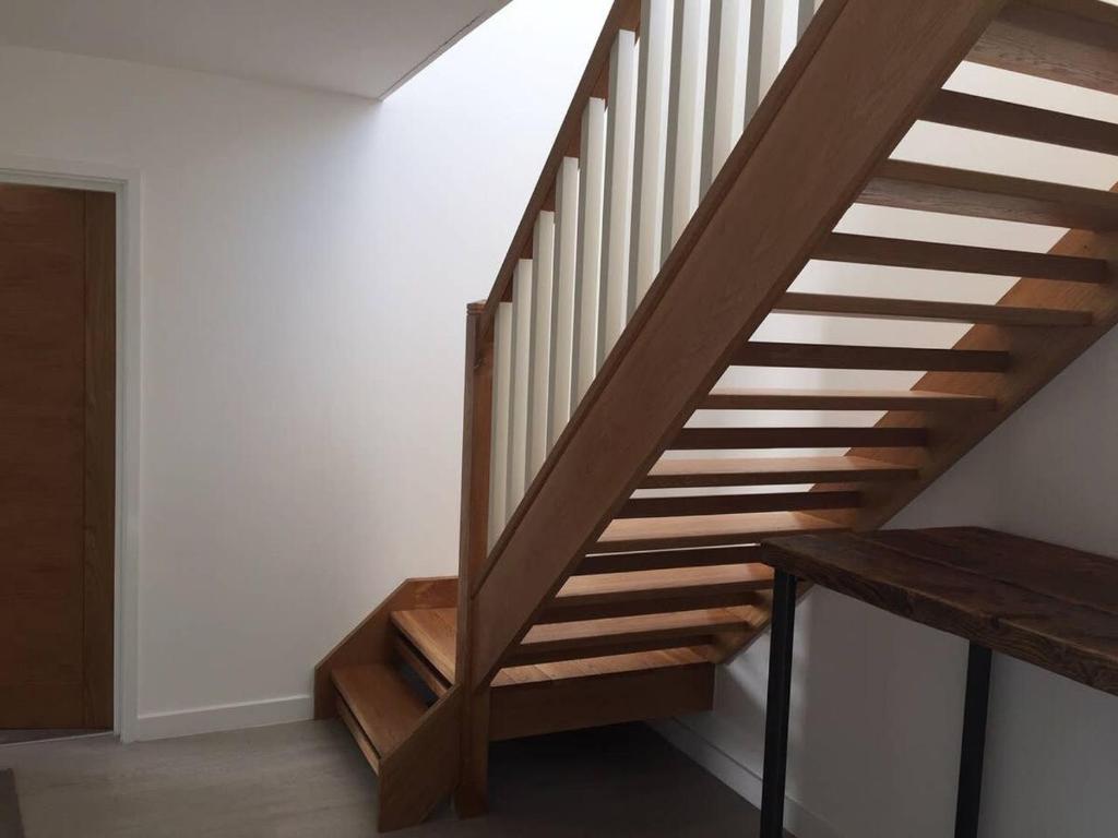 a wooden staircase in a room with a wooden table at Relax in style at my stunning Holywell Beach home in Holywell Bay