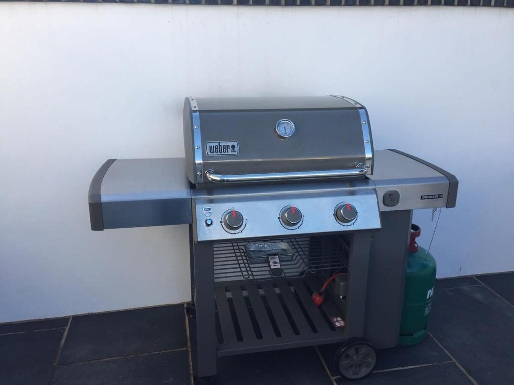a grill sitting on a table next to a wall at Relax in style at my stunning Holywell Beach home in Holywell Bay