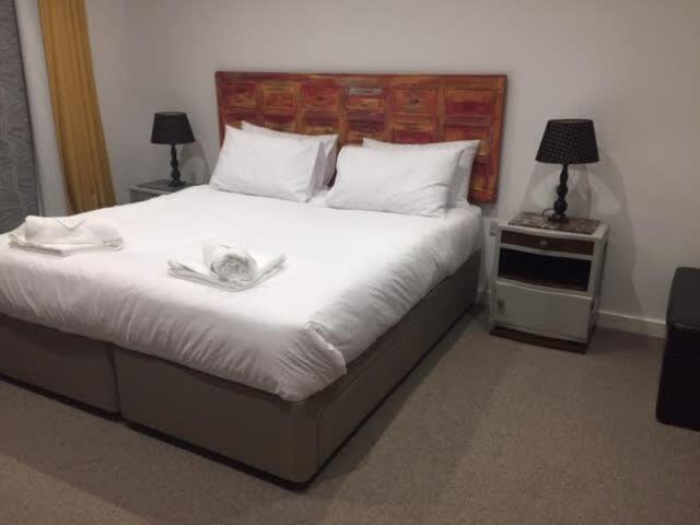 a bedroom with a large white bed with two lamps at Relax in style at my stunning Holywell Beach home in Holywell Bay