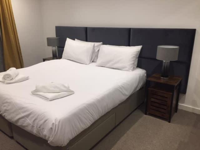 a bedroom with a large bed with white sheets and pillows at Relax in style at my stunning Holywell Beach home in Holywell Bay