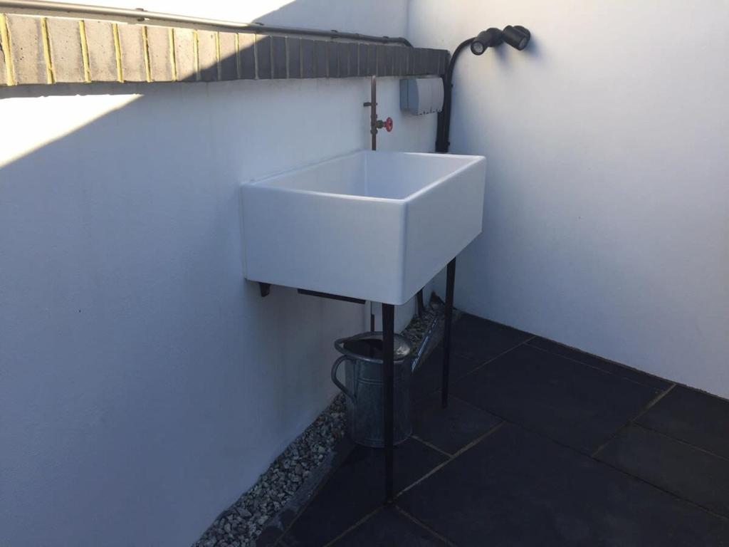 a white sink in the corner of a bathroom at Relax in style at my stunning Holywell Beach home in Holywell Bay