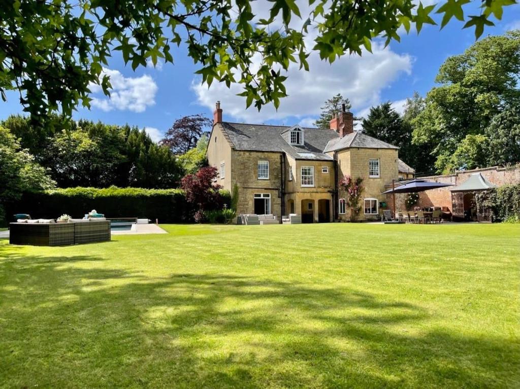 a large house with a large grass yard at Georgian Home with Heated Swimming Pool in Crewkerne