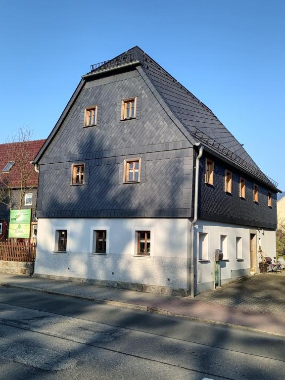 un grand bâtiment blanc avec un toit noir dans l'établissement Ökologische Ferienwohnung Becker, à Kottmar
