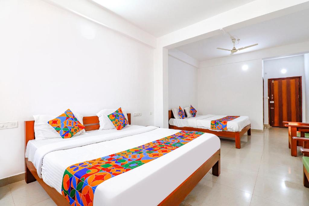 a hotel room with two beds and a table and chairs at FabHotel Raj Residency Madikeri in Madikeri