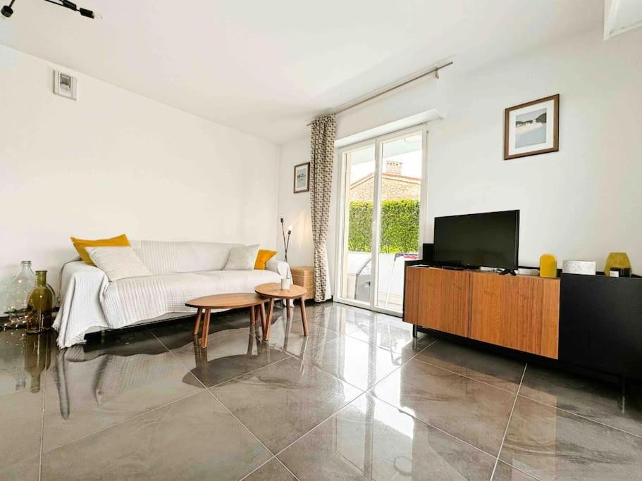 un salon blanc avec un canapé et une télévision dans l'établissement Le Mas des Oliviers : Apt 4 Prs, Piscine, Parking, à Antibes