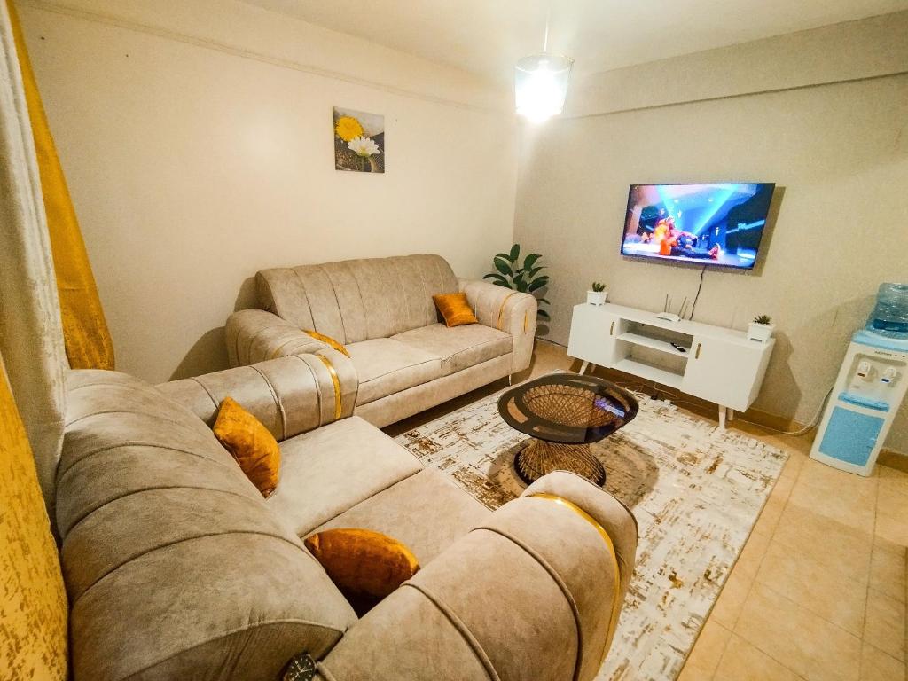 a living room with two couches and a flat screen tv at Cosy Homes Eldoret in Eldoret