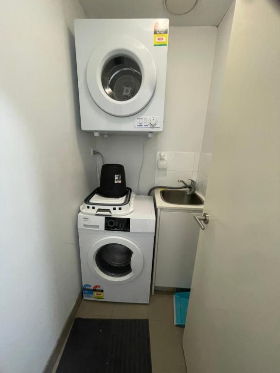 uma pequena casa de banho com uma máquina de lavar roupa e um lavatório em Ocean view 2 Bedroom apartment em Sydney