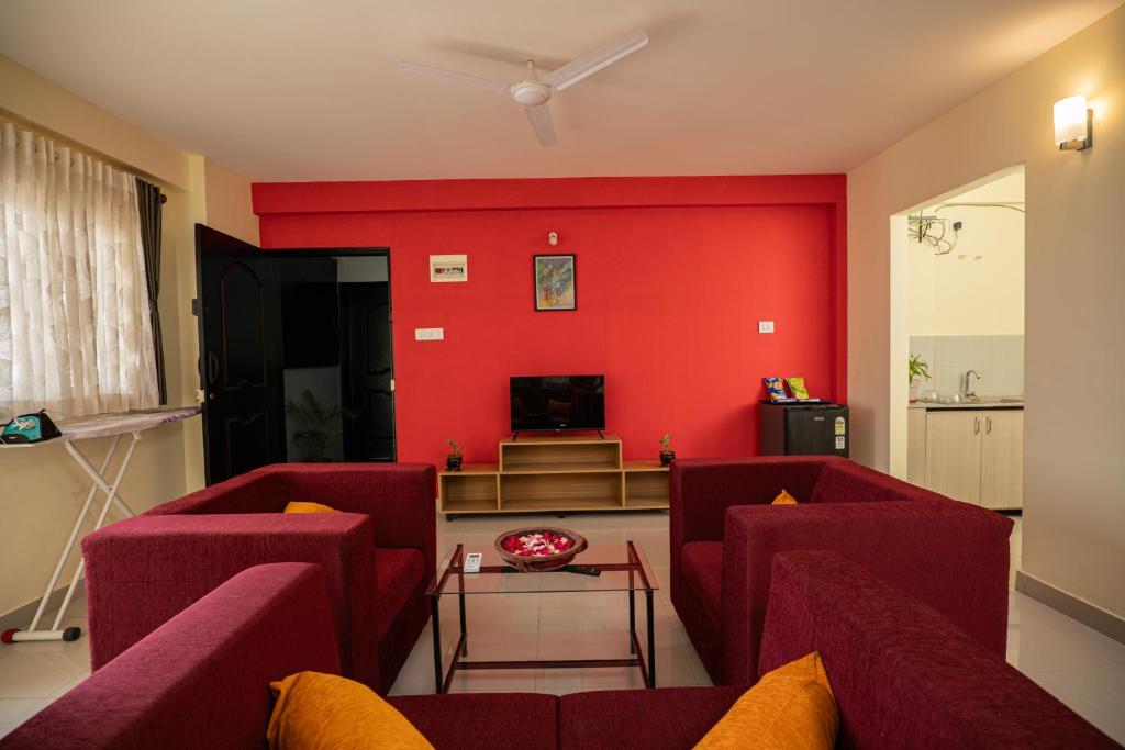 a living room with red walls and red chairs at Guesture Stays - Dwellington, Electronics City Phase 2 in Bangalore