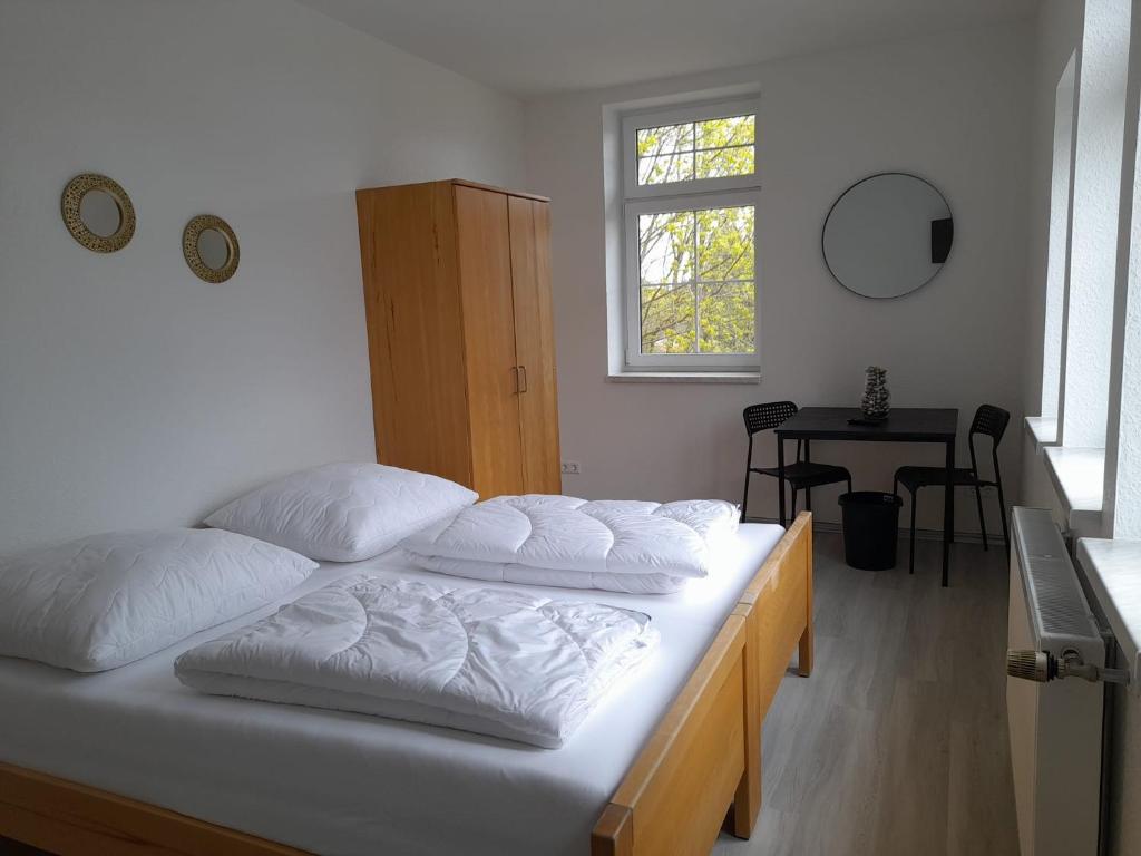 Un dormitorio con una cama con almohadas blancas. en Rennsteighostel Thal en Ruhla