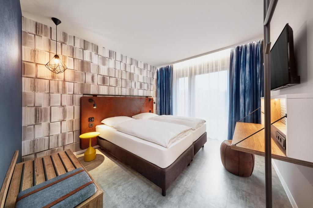 H2 Hotel Mainz في ماينز: غرفة نوم فيها سرير وتلفزيون