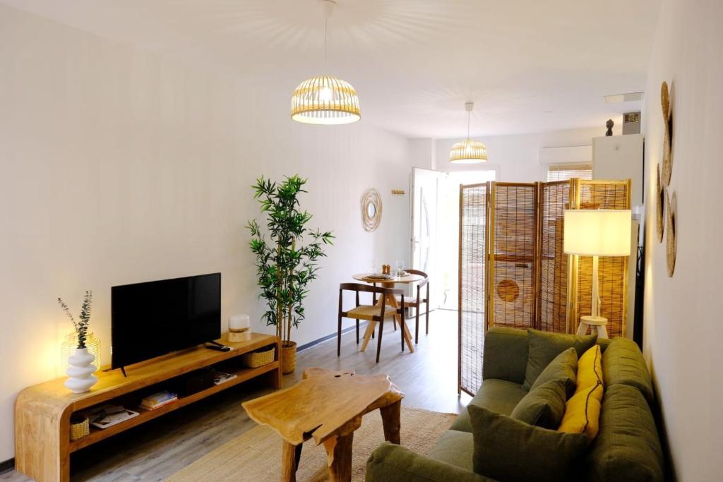 un salon avec un canapé, une télévision et une table dans l'établissement Maison « Ubud » love room spa, à Berre-lʼÉtang