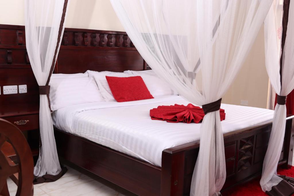 a bed with white sheets and red pillows at White Peacock Resort in Tezo