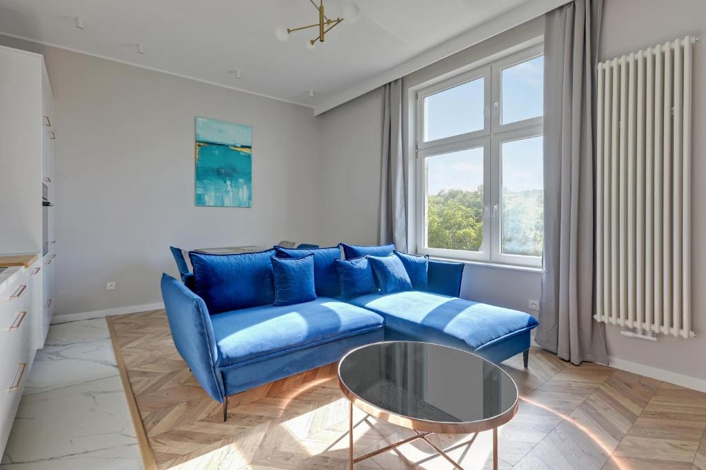 un soggiorno con divano blu e tavolo in vetro di Dom & House - Apartament Kościuszki Family a Sopot