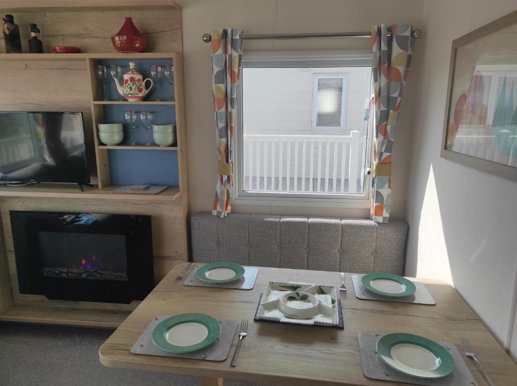 a living room with a table and a fireplace at Torbay Holiday Home at The Waterside Holiday Park - With Deck and Sea View in Torquay