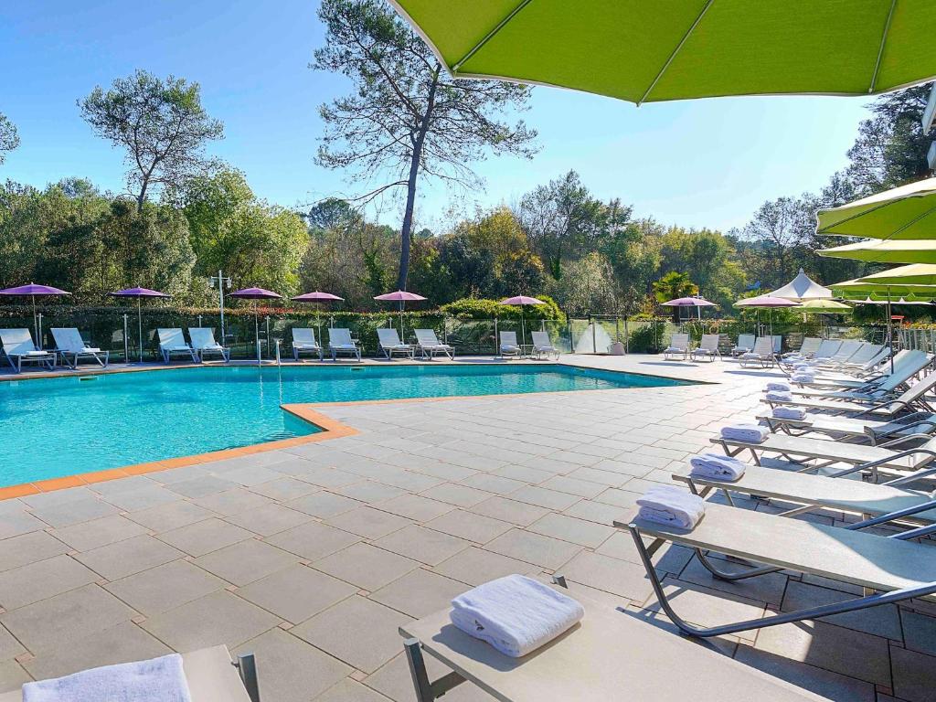 - une piscine avec des chaises longues et des parasols dans l'établissement Novotel Antibes Sophia Antipolis, à Valbonne