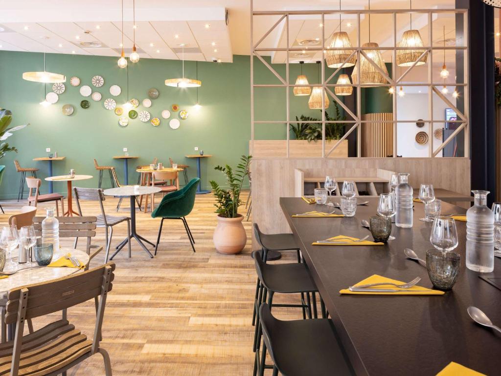 un restaurant avec des tables noires, des chaises et des tables dans l'établissement ibis Marseille Centre Euromed, à Marseille