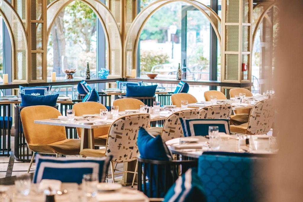 a restaurant with tables and chairs and windows at Hilton Imperial Dubrovnik in Dubrovnik