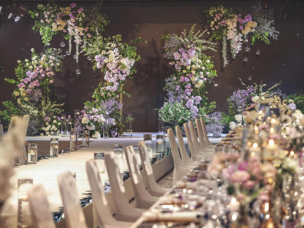 una mesa larga con sillas blancas y flores en Novotel Ambassador Seoul Dongdaemun Hotels & Residences, en Seúl