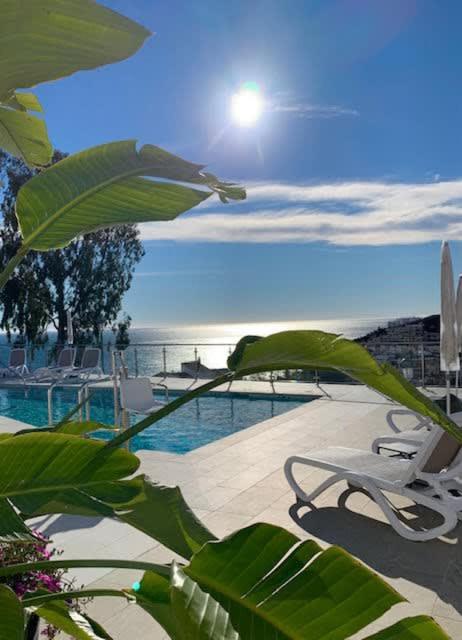 a pool with a chair and the sun in the sky at Casa Grace in Nerja