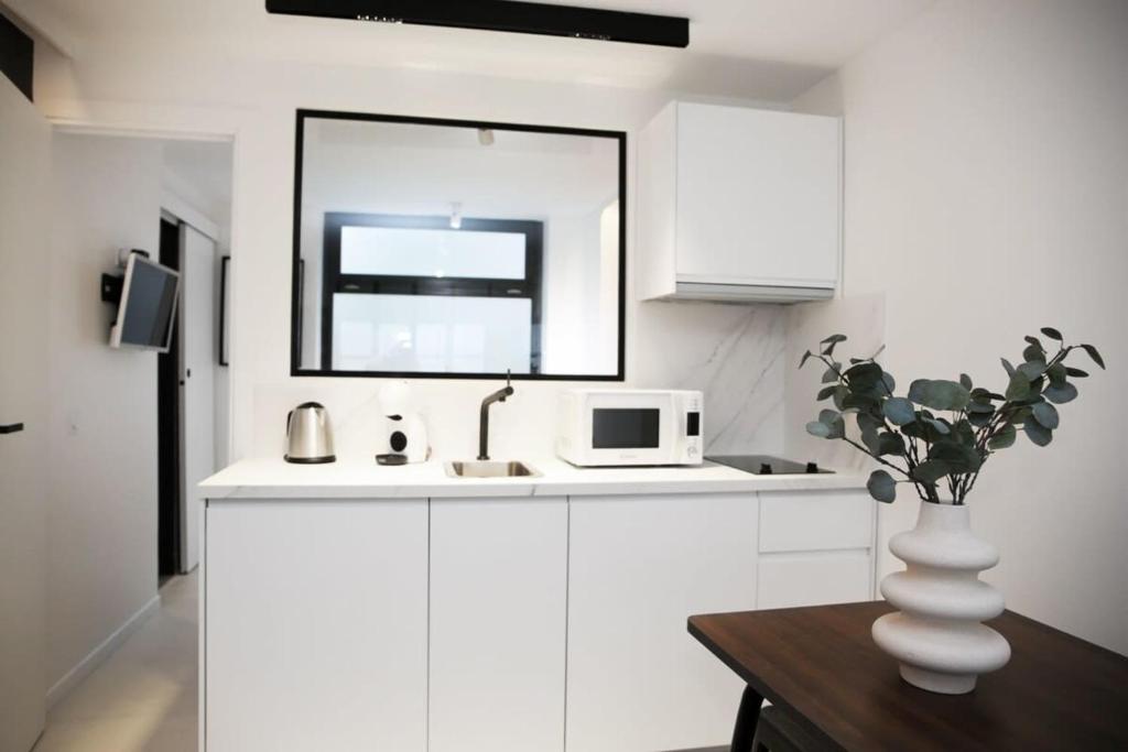 une cuisine blanche avec un évier et un micro-ondes dans l'établissement Logement Idéal en Famille - Porte du Marais - 6P - FLAT-GUEST, à Paris