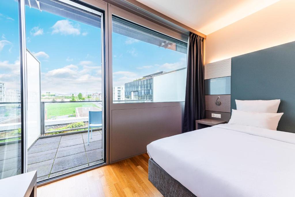 um quarto de hotel com uma cama e uma grande janela em B&B HOTEL Lausanne Crissier em Lausanne