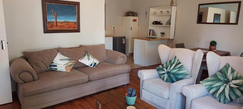 ein Wohnzimmer mit einem Sofa und 2 Stühlen in der Unterkunft Cicada's Call Guest Cottage in Nelspruit