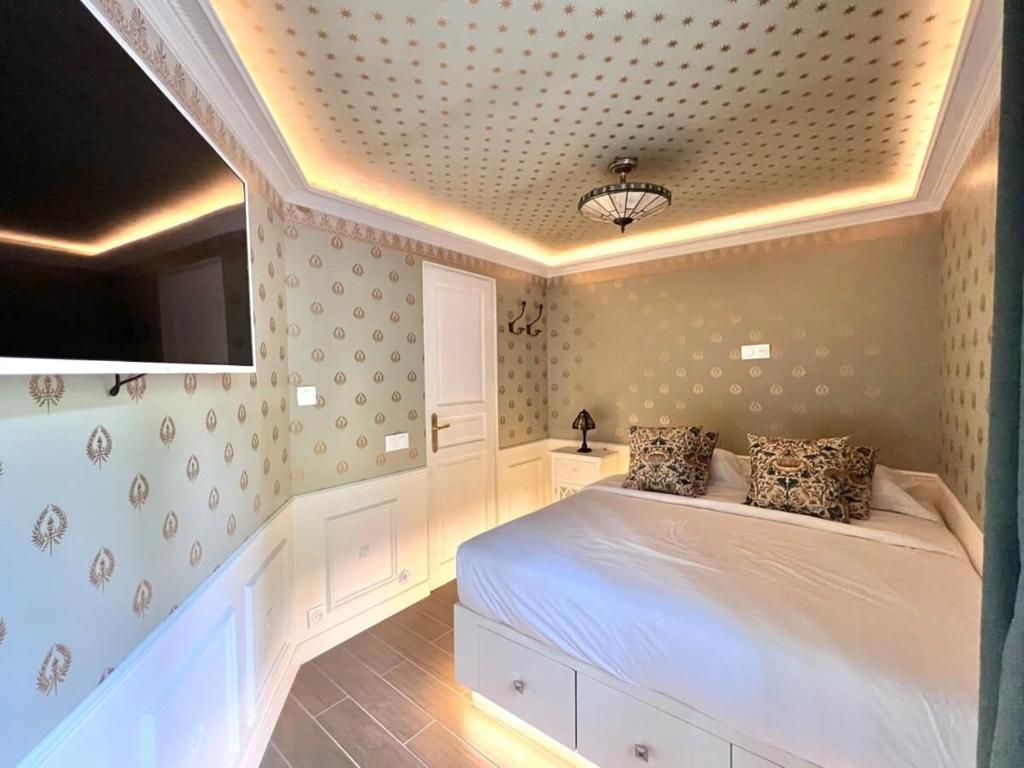 1 Schlafzimmer mit einem weißen Bett und einem TV in der Unterkunft Appartement prestige à deux pas de Montparnasse 6P in Paris