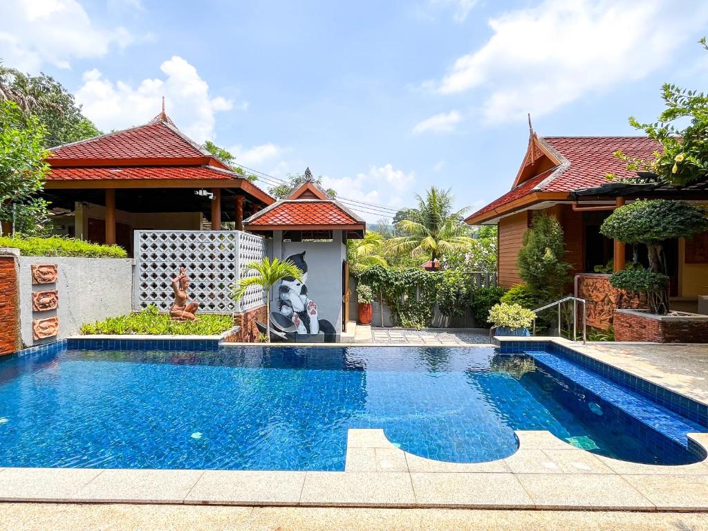 a villa with a swimming pool in front of a house at Baleeyan Residence in Thalang
