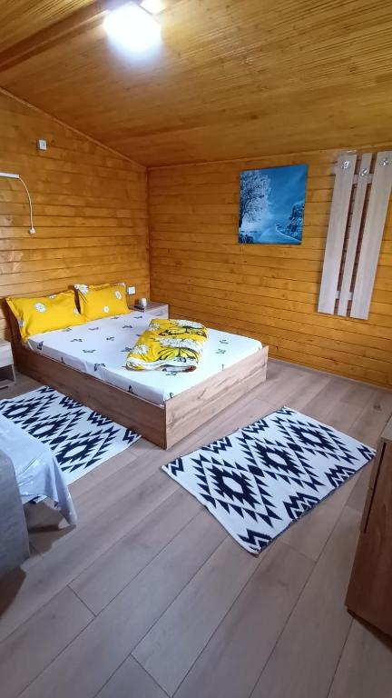 a bedroom with two beds and two rugs at Cabanutele La Denisa in Dubova
