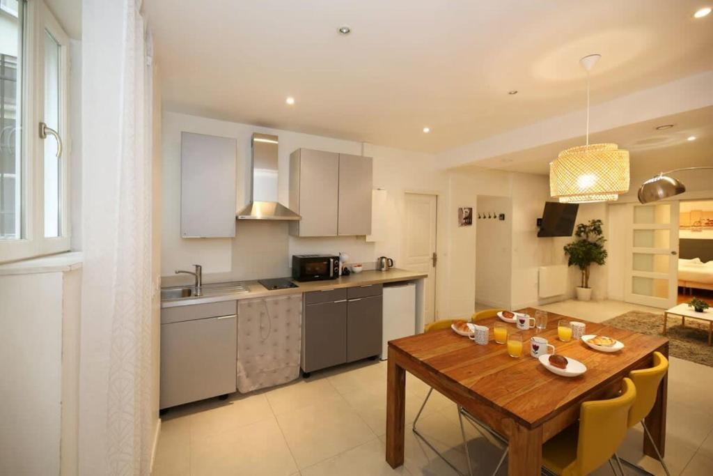 a kitchen with a wooden table with yellow chairs at RDJ - Appartement tout confort au cœur de Paris 5 in Paris