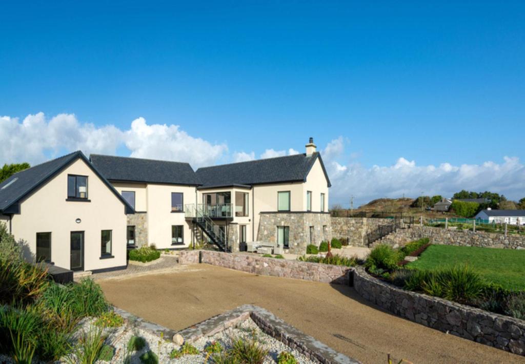 een groot wit huis met een stenen muur bij Sruthan Pier House in Carraroe