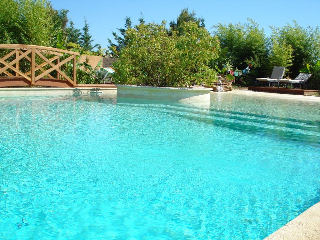 une grande piscine d'eau bleue dans une cour dans l'établissement Le Patio, à Laouque