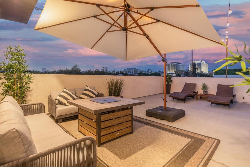 a patio with a table and an umbrella at Periwinkle by AvantStay Walk to Staples Rooftop in Los Angeles